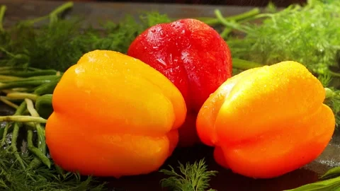 Drops of water fall from above on three sweet peppers, orange, red, yellow Stock Footage 239845202