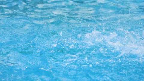 Drops of water fall on the blue surface of the water creating splashes. Stock-Footage 313378977