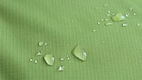 Drops of water fall on the green waterproof fabric rip-stop. Close-up Video stock 76300161