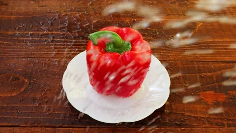 Drops of water fall on a pepper lying on a white plate Stock Footage 236542042