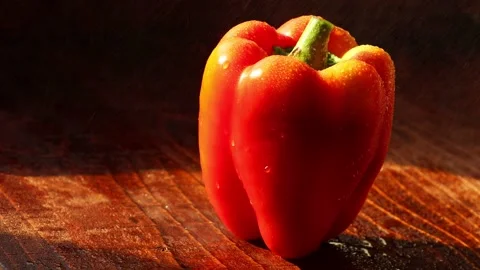 Drops of water fall on a pepper lying on a wooden background Stock Footage 239845547
