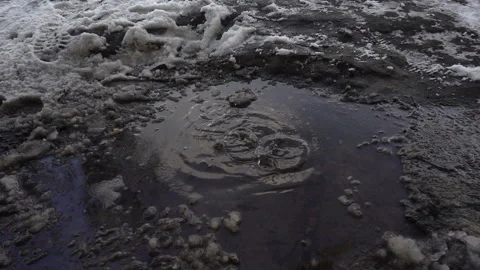 Drops of water fall into a puddle with snow in slow motion. Stock Footage 212452642