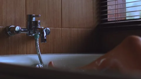 Drops of water flow down the leg, the foot turns off the water tap, turning off Видео 256563202