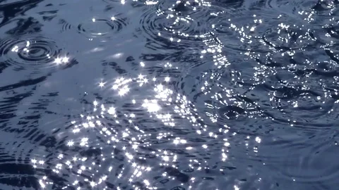 Drops of water on glittering lake surface. Slow motion Video stock 76757210