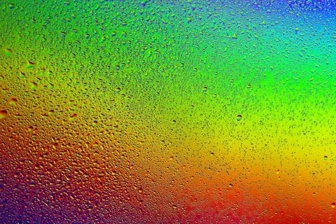 Drops of water on a rainbow background. Stock Photos