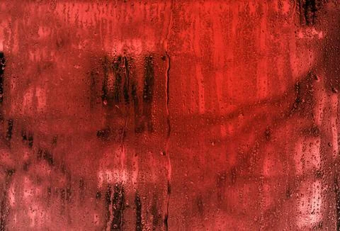 Drops of water run down the wet glass. red background. abstract background .. Foto stock