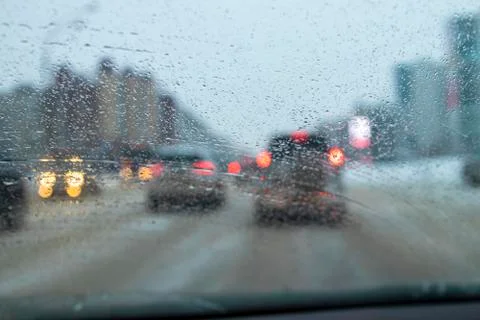 Drops of water from thawed snow on a machine glass. Bad visibility. Caution w Stock Photos