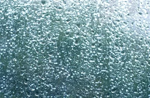 Drops on the window glass. Blurred background of street rain in the rays of t Stock Photos