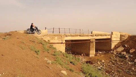 Drought Dries River Completely as Lone Man on Motorcycle Crosses Old Bridge Stock Footage 318526132