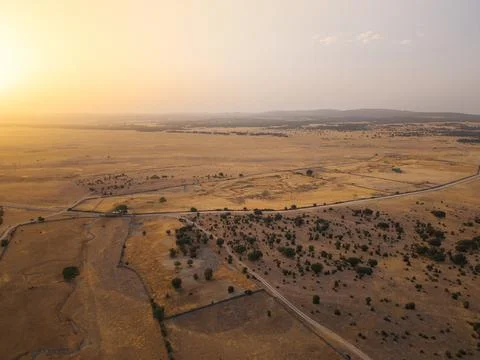 Drought-stricken dehesa with dry fields and road in Salamanca Stock Photos