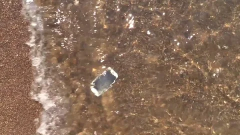 Drown smartphone float on bottom in waves of sea surf sandy beach. Stock Footage 79161631