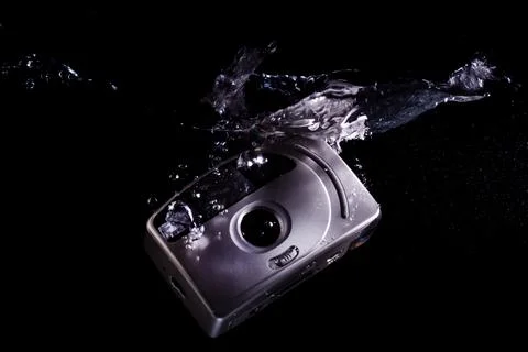Drowning analog camera symbolizing technological evolution Stock Photos