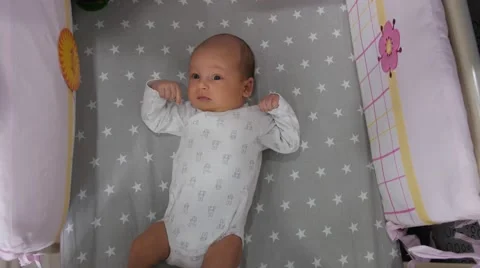 Drowsy child in a crib moving hands and legs and yawning. Handheld shot Видео 67173851