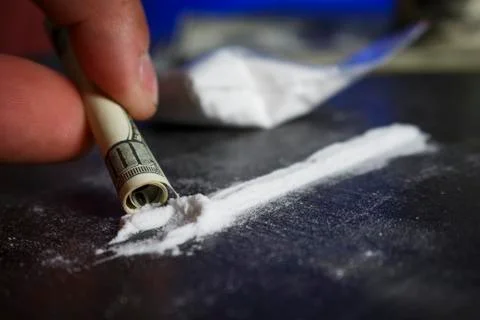 Drug addict man using narcotics, sniffing cocaine lines white powder with rol Stock Photos