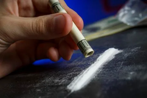 Drug addict man using narcotics, sniffing cocaine lines white powder with rol Stock Photos
