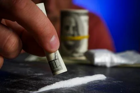 Drug addict man using narcotics, sniffing cocaine lines white powder with rol Stock Photos