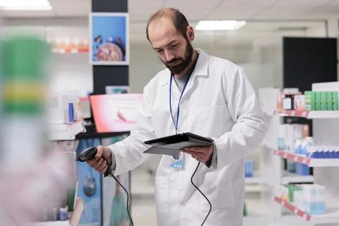 Drugstore worker checking medication information on tablet computer while Stock Photos