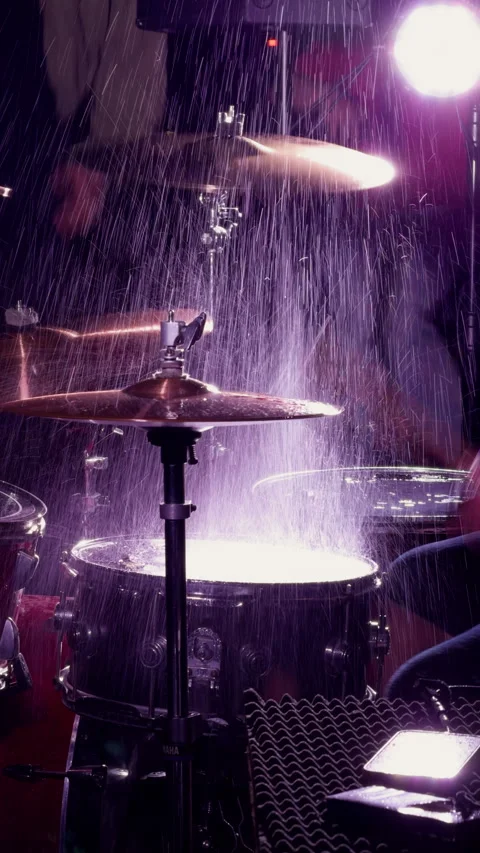 Drum kit under rain spray with cymbal strike and purple stage light in dark Stock Footage 344973587