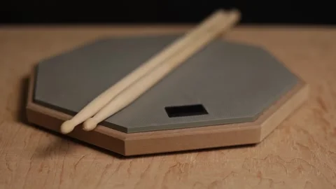 Drum practice pad with sticks resting on a wooden surface Stock Footage 341737487