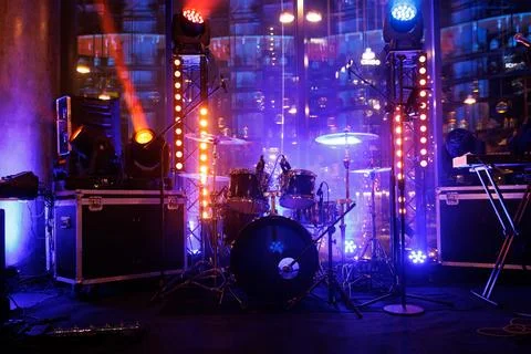 Drum set ready for band performance under vibrant stage light. Stock Photos