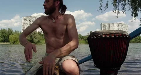 Drummer hands playing on a makeshift drum on a background of lake and building Stock Footage 50454723