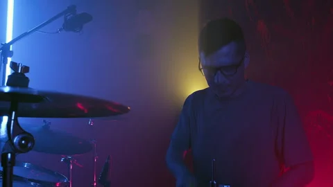 Drummer hits drums in neon light. Drummer rehearsing on drums in a studio. Close Stock Footage 258130219