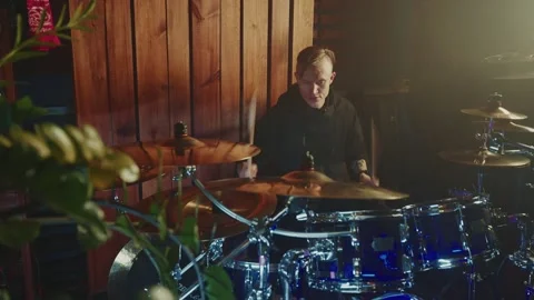 Drummer performs energetic music in small venue surrounded by plants Stock Footage 305848401