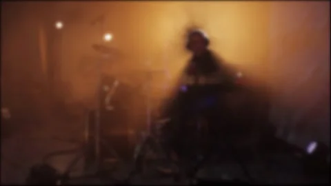 A drummer plays a drum kit on stage against a backdrop of smoke and spotlights Stock Footage 312595355