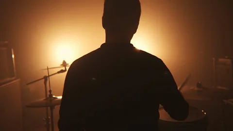 Drummer plays the drum set in the dark and in the fog in front of the spotlight Stock Footage 105455009