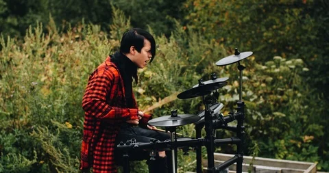 The drummer plays electronic drums in the forest. Behind him trees Stock Footage 114519772