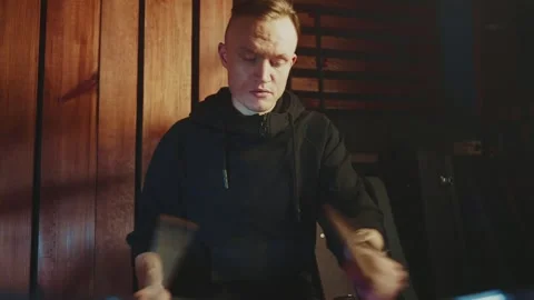 Drummer practices rhythm in a cozy, dimly lit studio environment Stock Footage 295331573
