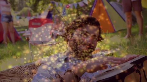 Drummer reclining and playing djembe in camp, golden sparks rising over drummer Stock Footage 333936798