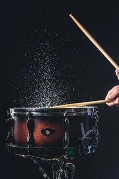 Drummer using drum sticks hitting snare drum with splashing water. Stock Photos