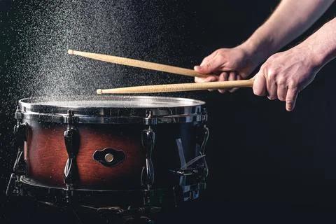 Drummer using drum sticks hitting snare drum with splashing water. Stock Photos