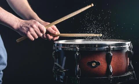 Drummer using drum sticks hitting snare drum with splashing water. Stock Photos