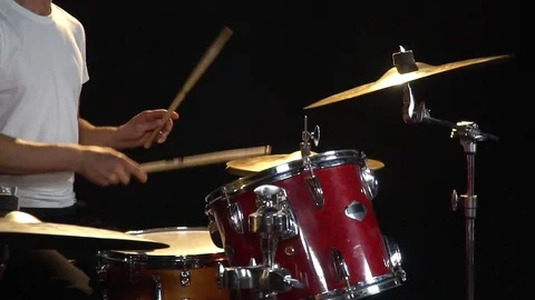 A drummer in a white T-shirt is sitting on a chair and playing with drum sticks Stock Footage