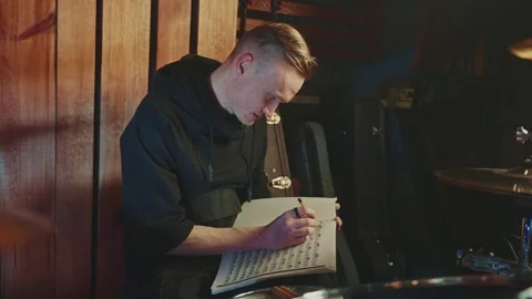 Drummer writing notes while rehearsing in a studio Stock Footage 295331430
