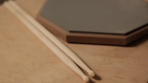 Drumsticks resting on a practice pad and wooden surface Vidéo 341737489