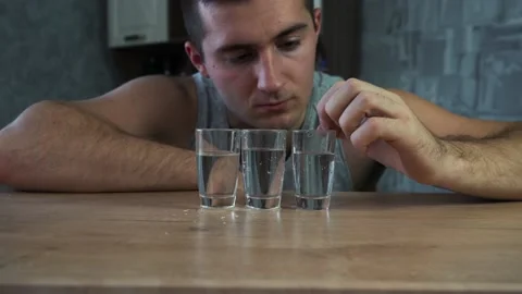 Drunk alcoholic sits at the table and looks at vodka Stockbeeldmateriaal 143927328