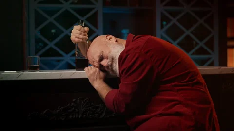 Drunk bearded man in his 50s asleep at bar counter with bottle, crisis Stock Footage 346714080