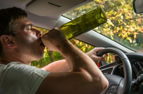 Drunk driver with bottle of wine driving a car - vehicle, alcohol and driving Stock-Fotos