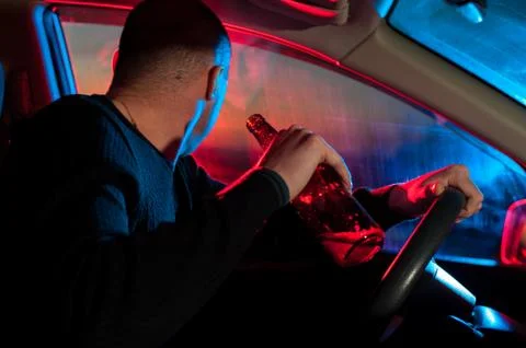Drunk driver in car with alcohol bottle Stock Photos