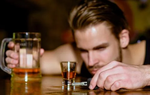 Drunk driver with car key. Alcohol problem. Lonely man drinking before driving Stock Photos