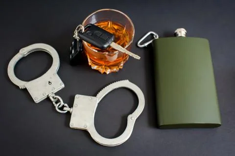 Drunk driving. Alcohol, car keys, handcuffs on a black background Stock Photos