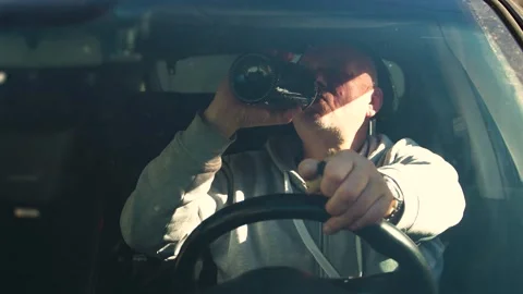 Drunk driving. The driver drinks strong alcohol while driving. Stock Footage 320357257