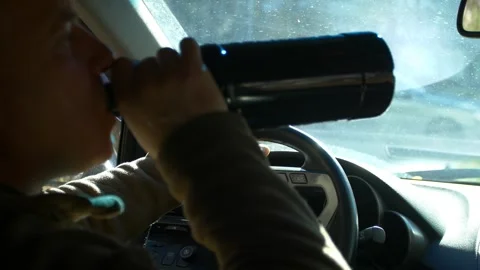 Drunk driving. The driver drinks whiskey while driving. Stock Footage 320356675