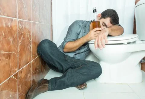 Drunk hispanic man sleeping over the toilet bowl Stock Photos
