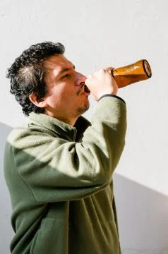 Drunk man with an alcohol problem standing up taking beer from a bottle. Stock Photos