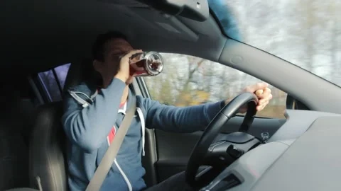Drunk man with bottle of alcohol drink driving on a road in the car Stock Footage 145369643