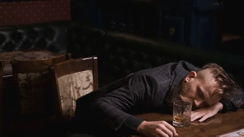 Drunk man fell asleep at table with glass of whiskey,looks bad and upset Stock Footage 129801885